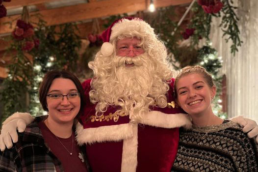 Two girls posing for a photo with Santa