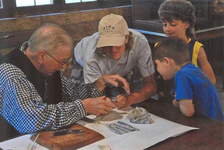 A group of people looking at a paper while a elderly old person walking thru history
