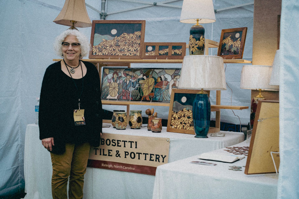A lady standing with Tile and pottery crafts