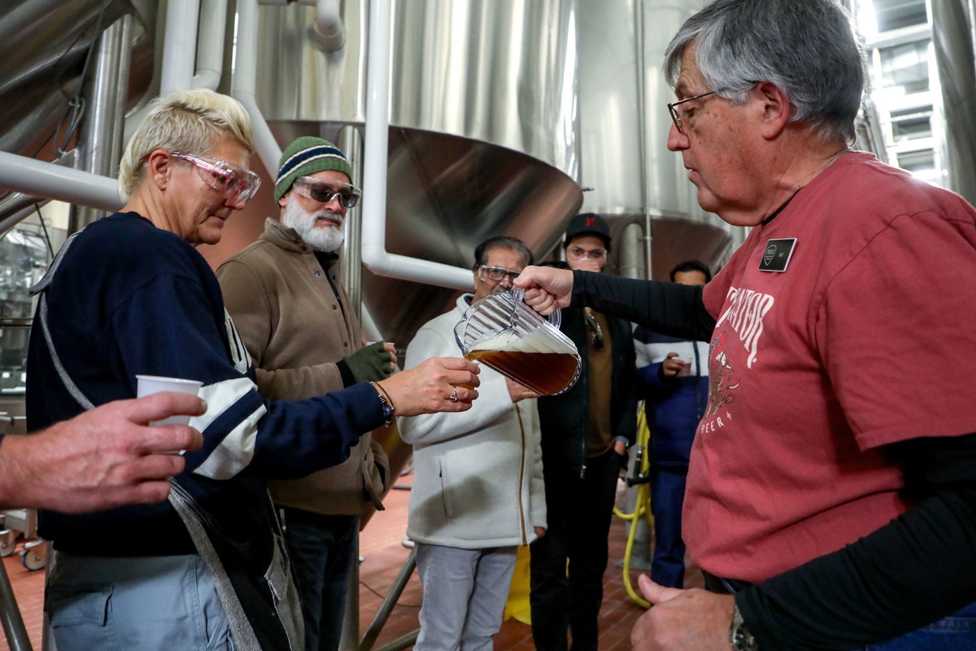 a person pouring beer from a jar to Tour taking patrons at Troegs independent brewing