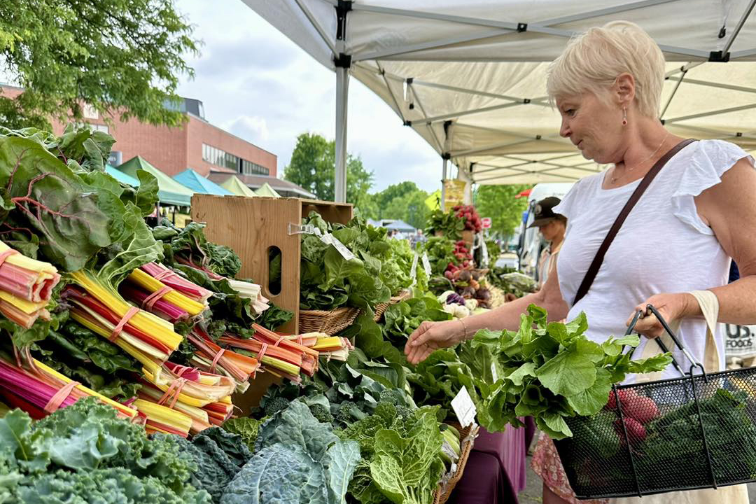 a lady buying green leafy vegetables at Easton Farmers Market